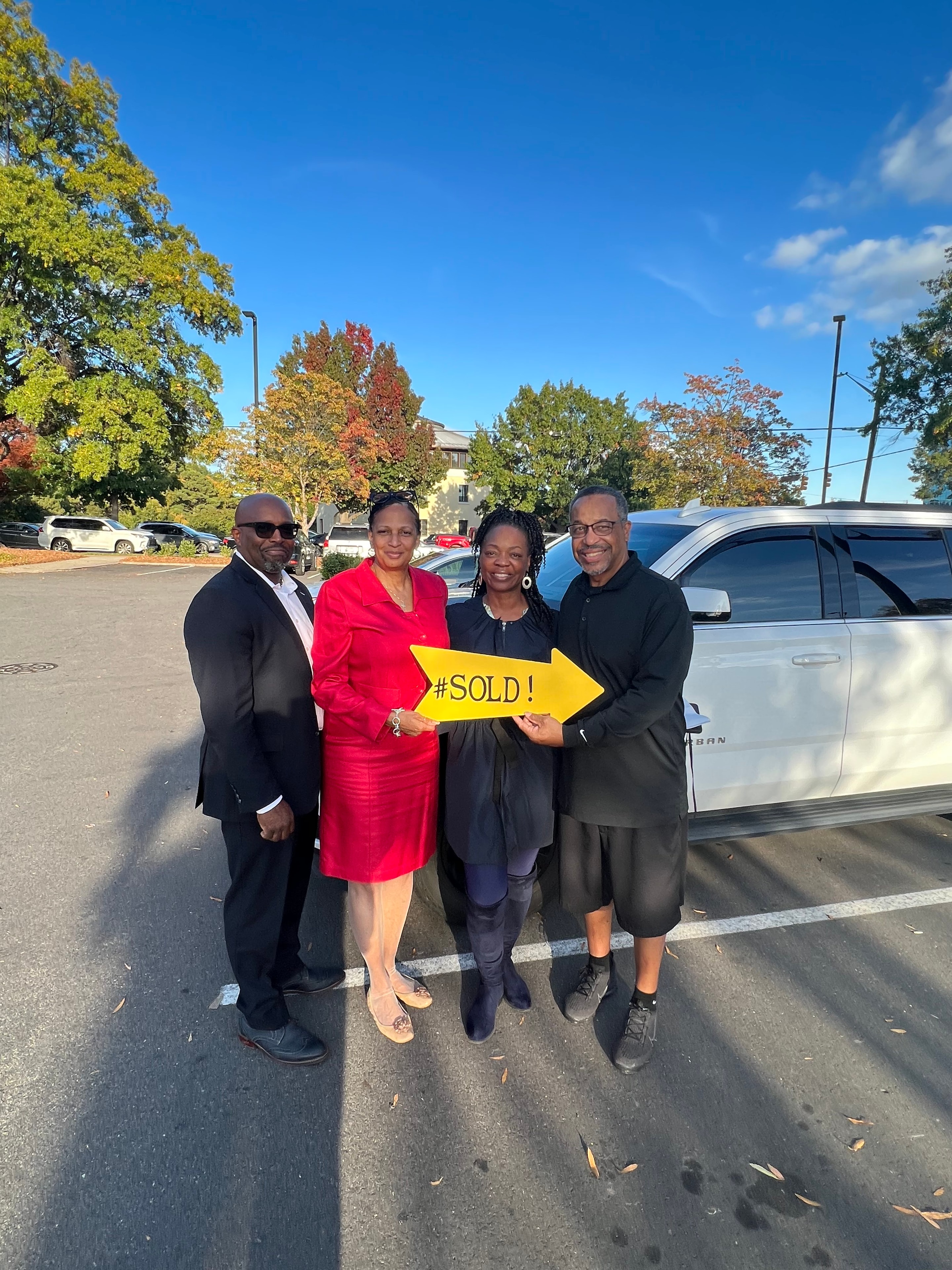 Commission Realty team and clients celebrating outside holding a #SOLD arrow sign