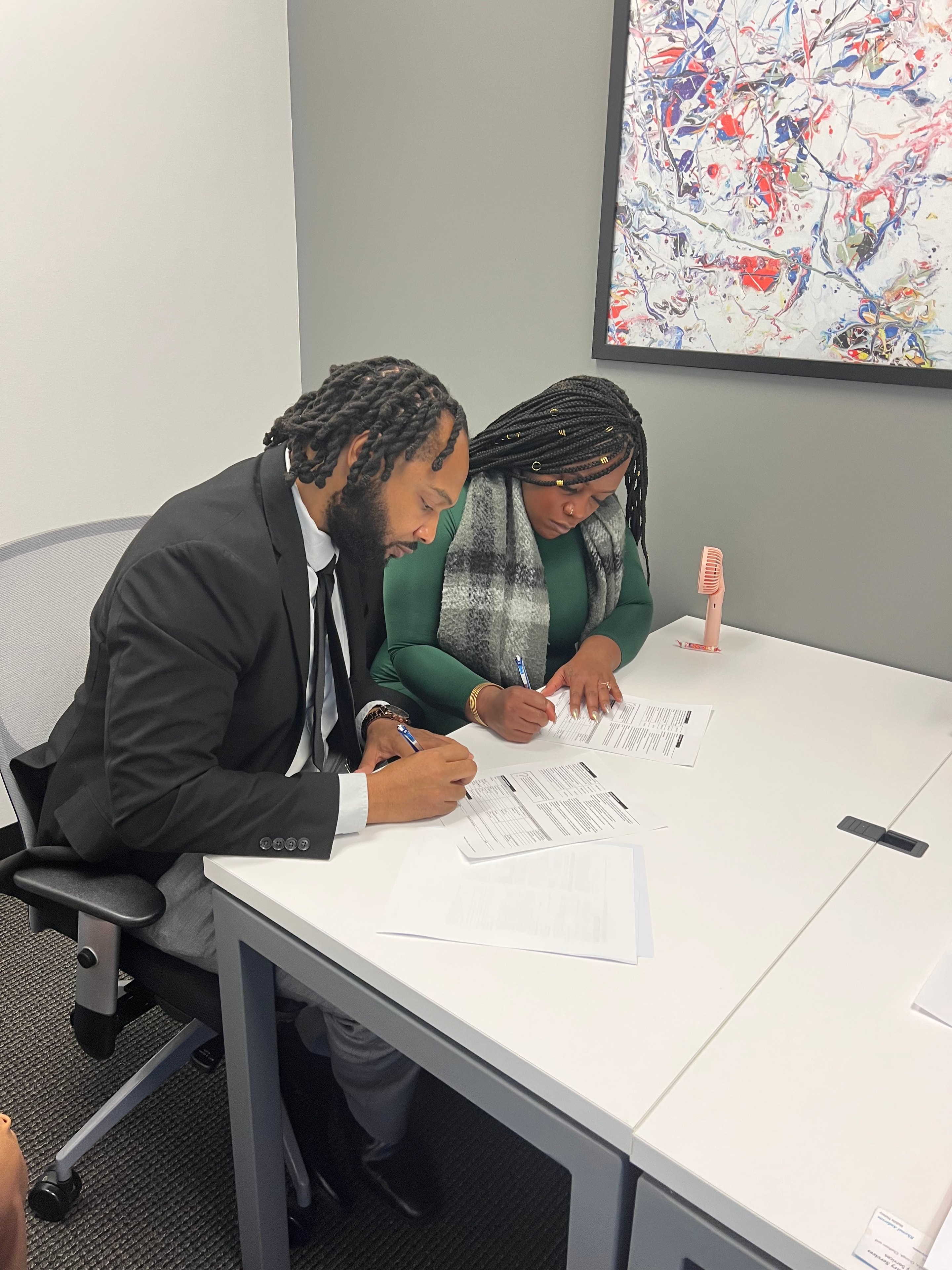 Patrick Dunn Sr. and client at the closing table holding a We Said Yes to the Address sign