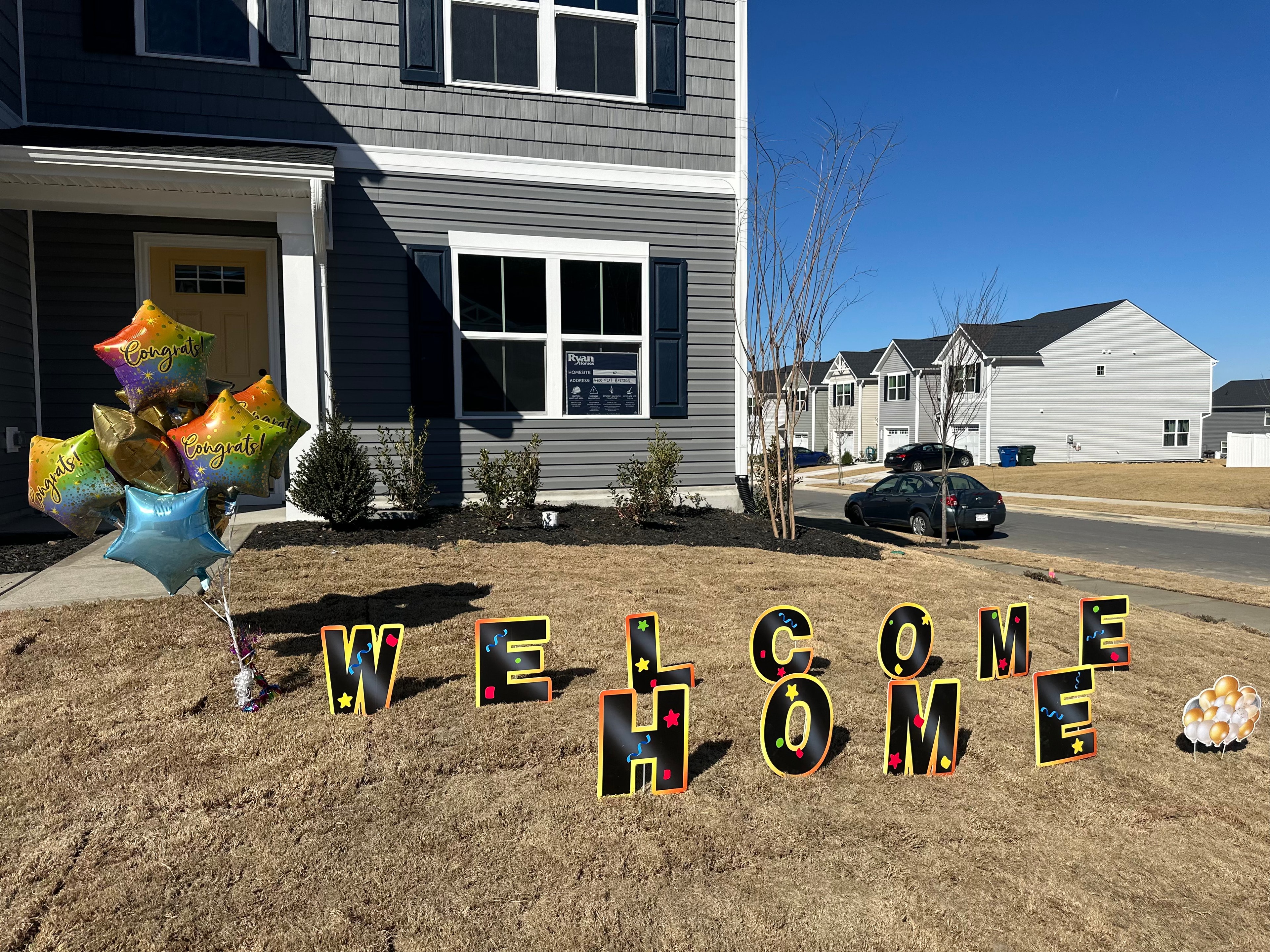New home with Welcome Home yard sign and Congrats balloons out front